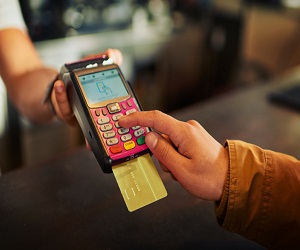 Closeup of an unrecognizable person paying their bill with a card machine inside of a restaurant during the day